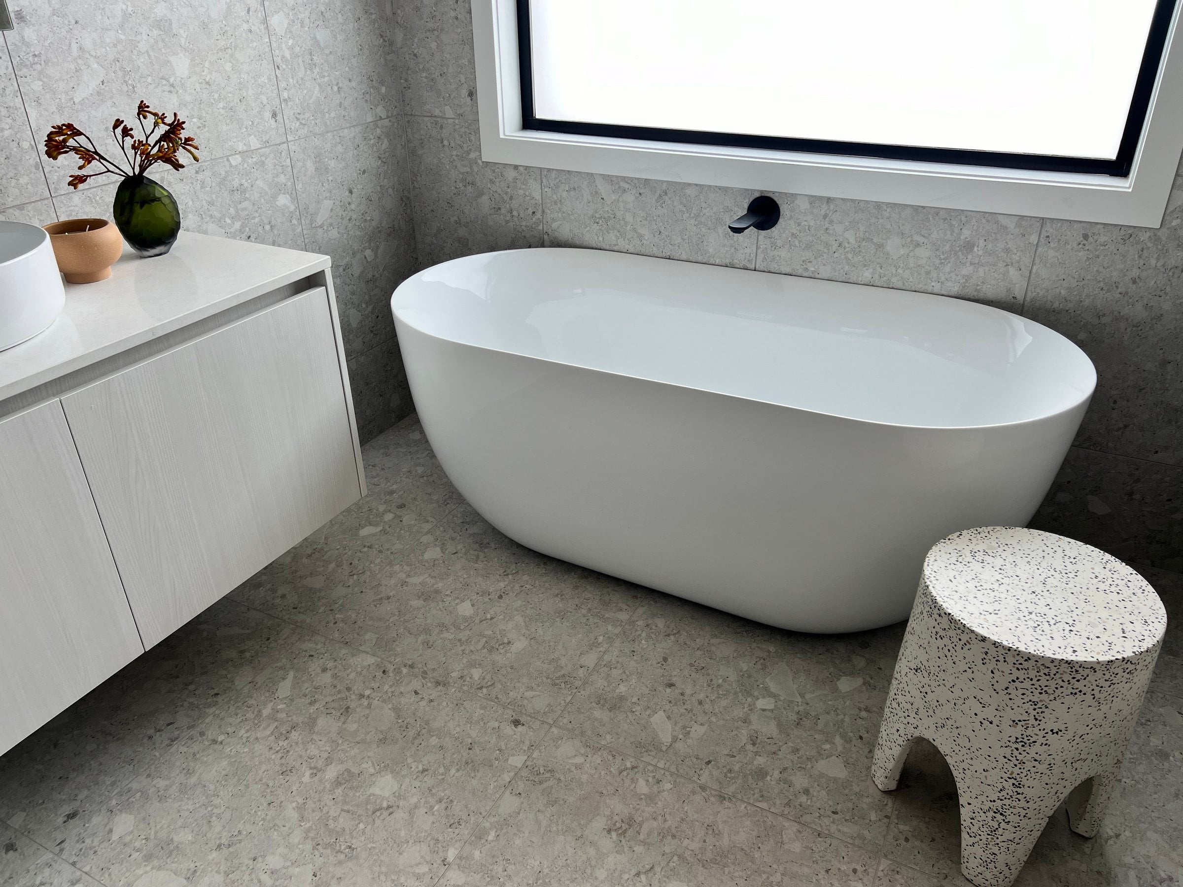 Freestanding bath beside a floating vanity on terrazzo-look tiles, Hampton